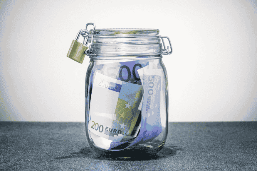 Glas mit Euro-Scheinen und Vorhängeschloss als Symbol für finanzielle Rücklagen zum Jahreswechsel